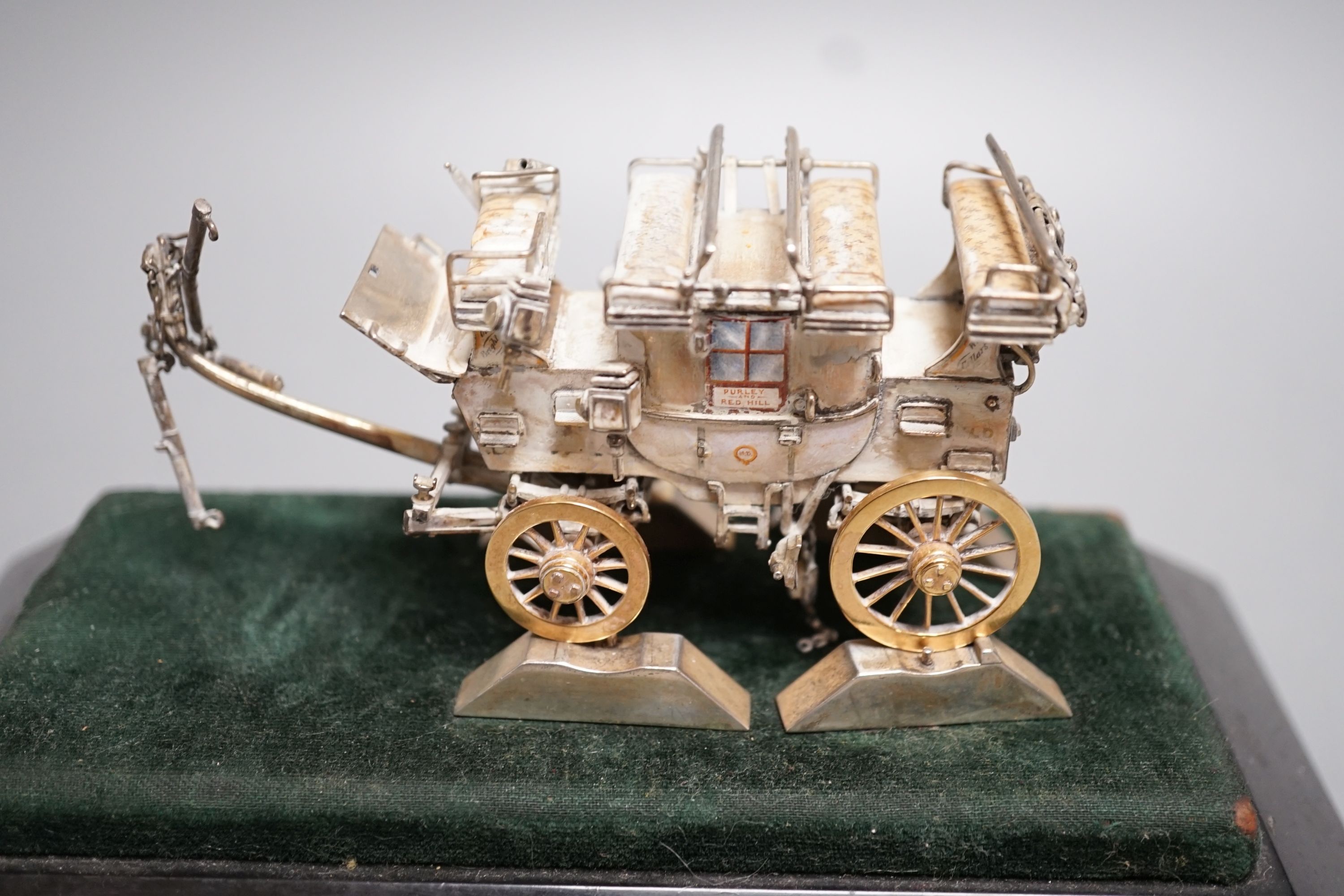 A parcel gilt white metal and enamelled miniature model of 'The Old Times Coach Made To Commemorate Jim Shelby's Record Run To Brighton and Back, 13th July, 1888', on plinth base with engraved inscription, overall 12.8cm